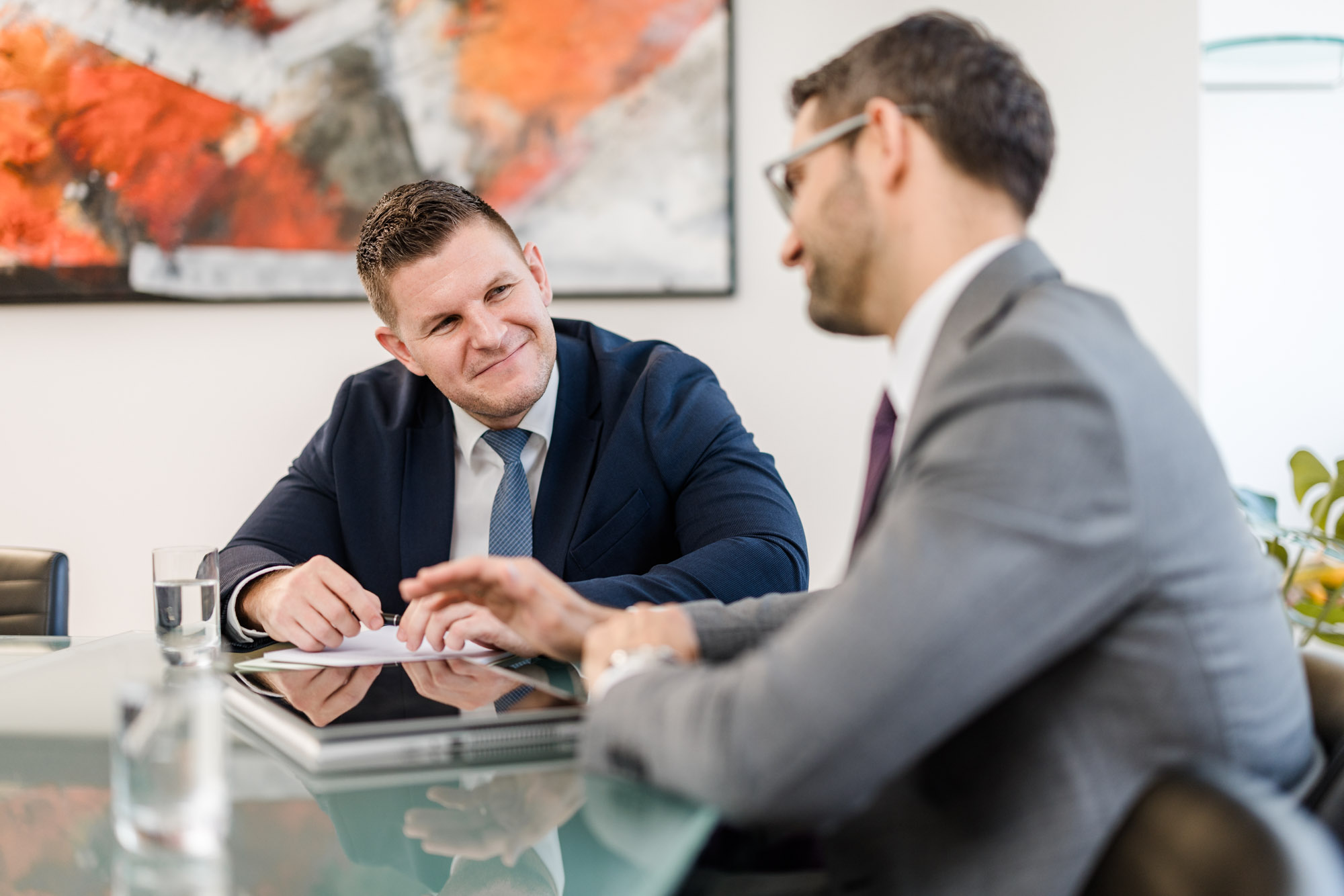 Zwei Männer sitzen an einem Tisch und besprechen ein Dokument