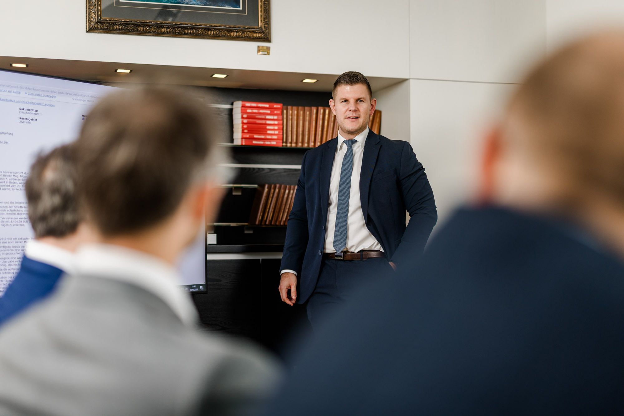 Anwalt hält eine Präsentation und sieht auf Personen am Tisch