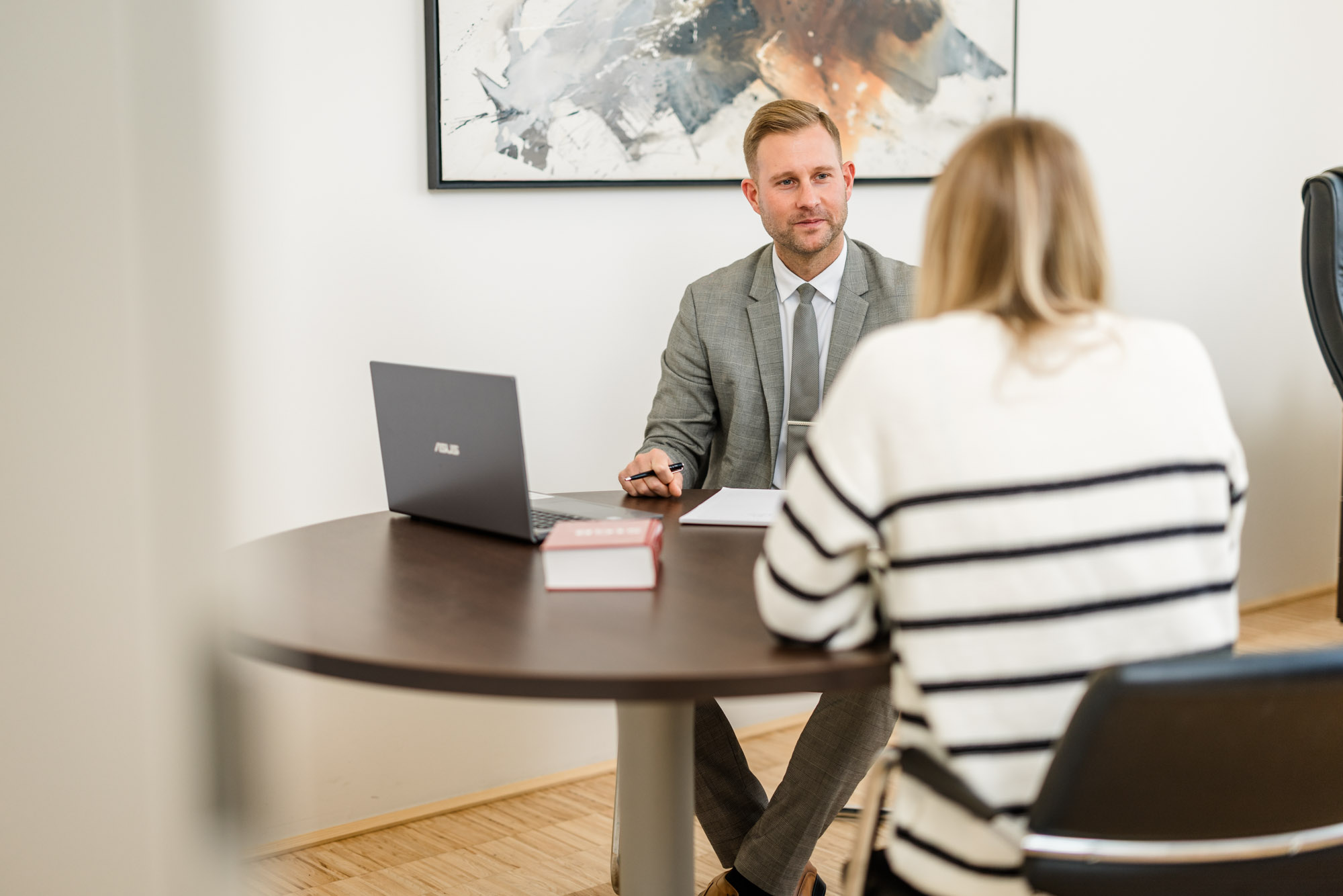 Anwalt sitzt mit einer Frau auf dem Tisch und hört ihr zu
