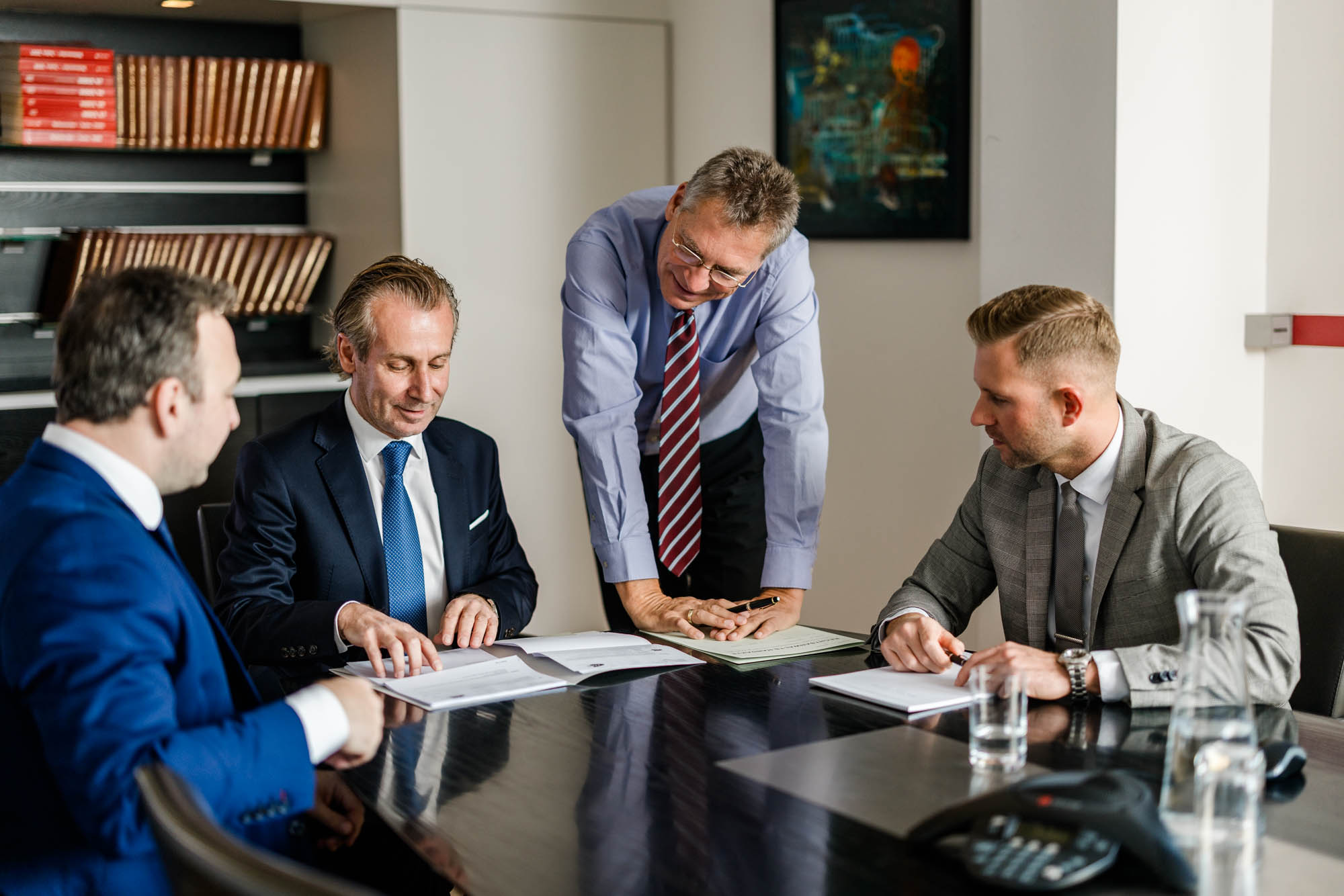 Vier Anwälte arbeiten an einem Tisch gemeinsam an einem Dokument