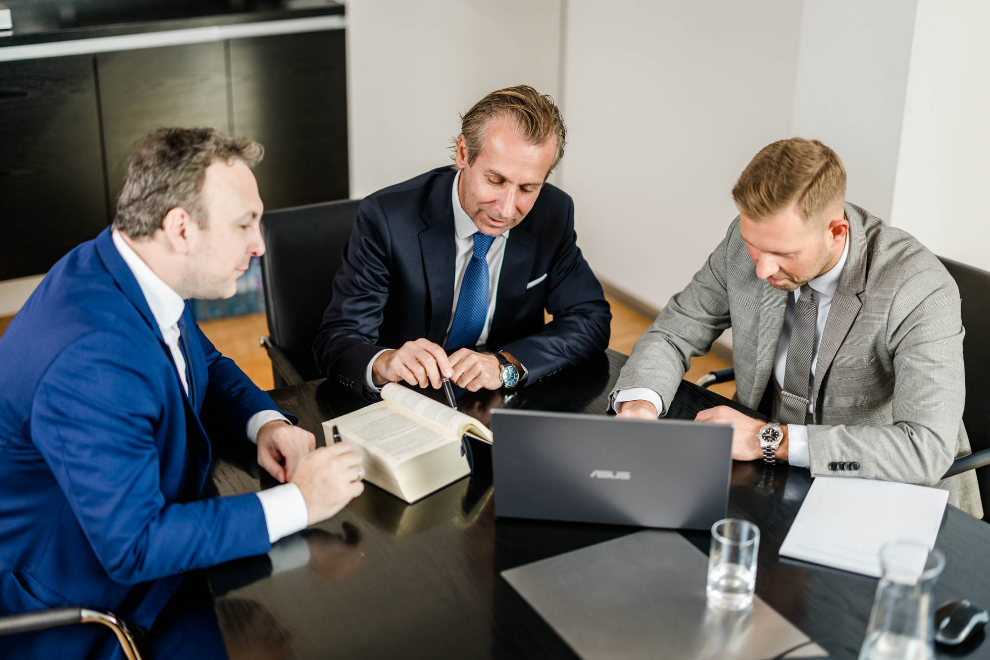 Drei Anwälte besprechen gemeinsam etwas aus dem Gesetzbuch am Tisch