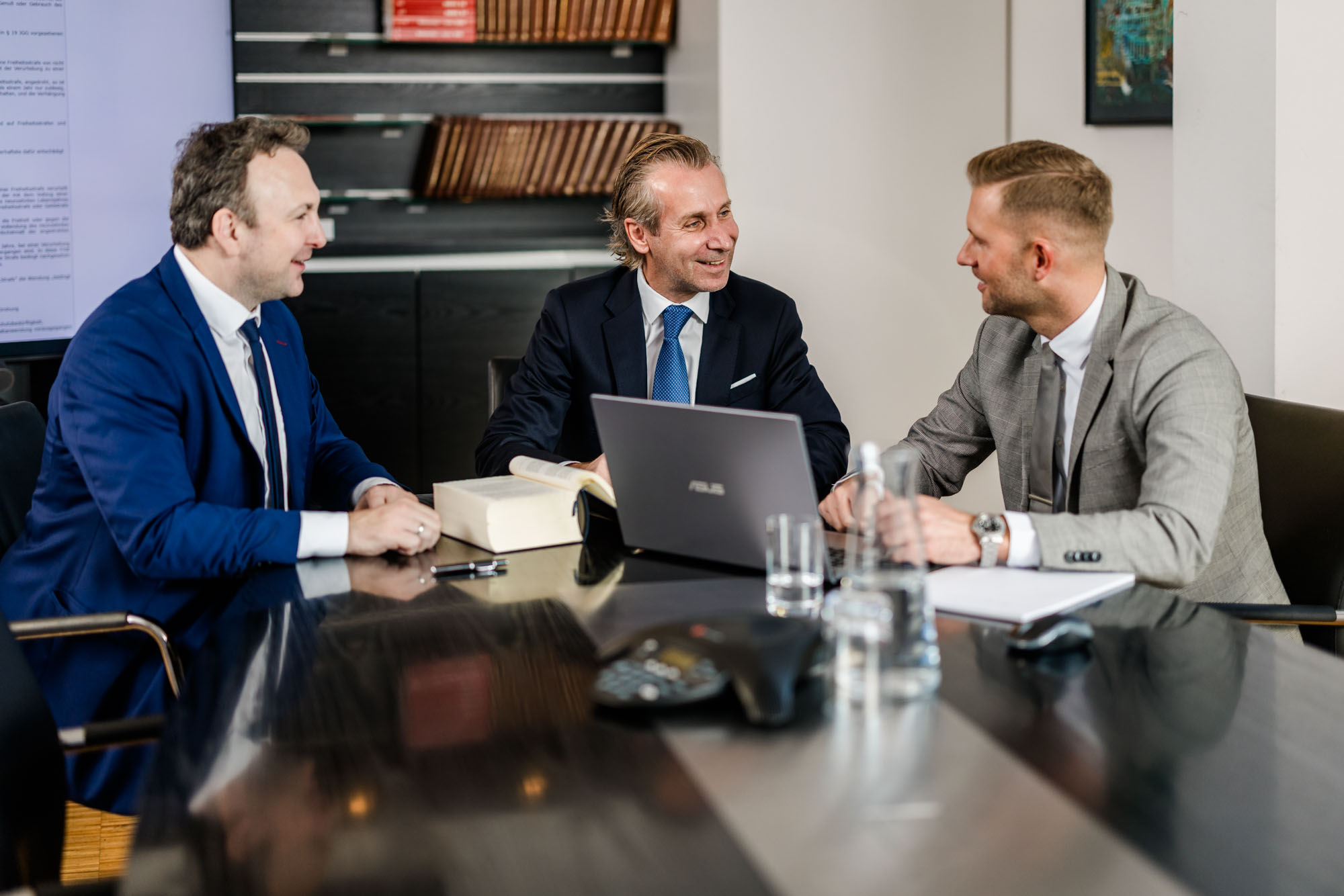 Drei Anwälte haben eine Besprechung mit Laptop am Tisch.