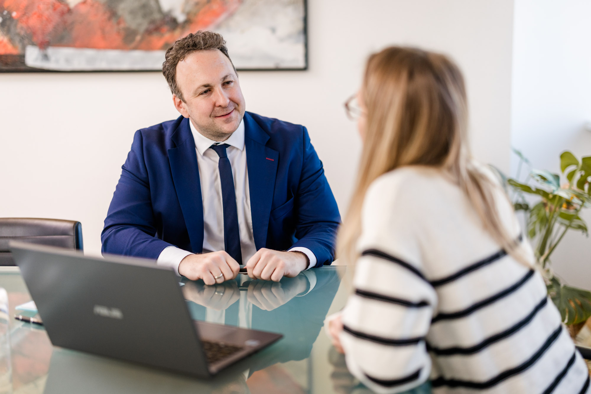 Anwalt spricht mit einer Dame und lächelt.