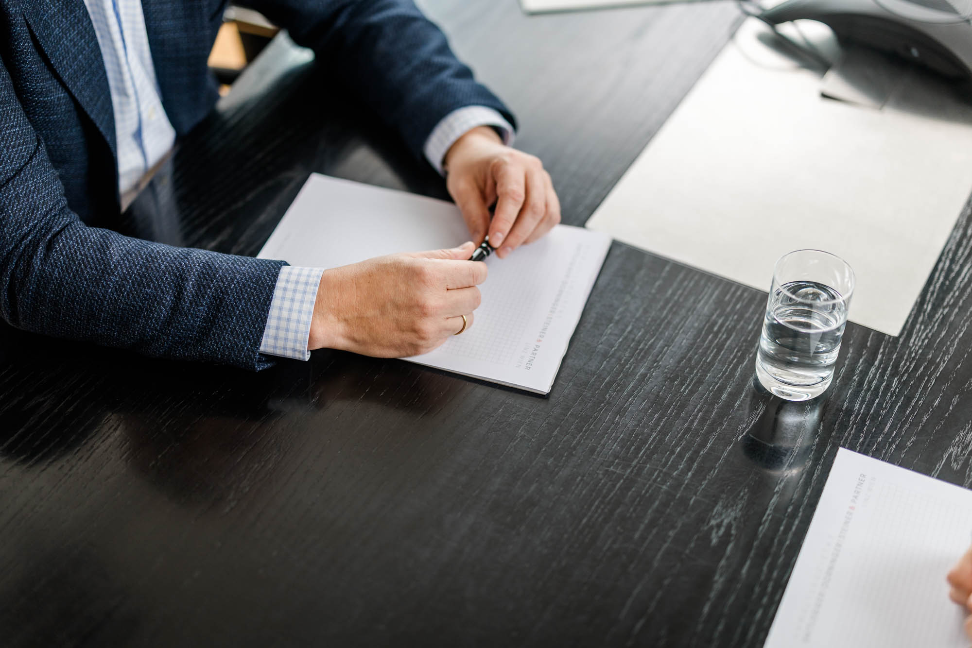 Hände mit Stift in der Hand liegen auf einem Dokument auf einem Tisch